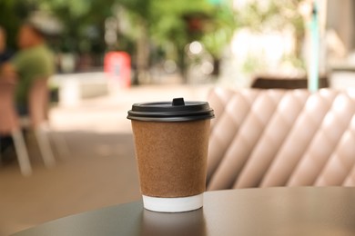 Paper cup of aromatic coffee on wooden table outdoors