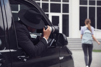 Photo of Private detective with camera spying from car