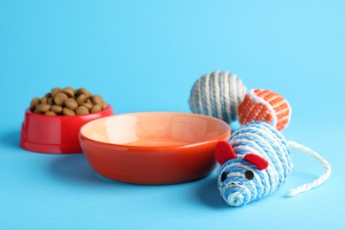 Photo of Feeding bowls and toys for pet on light blue  background