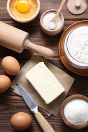 Photo of Making shortcrust pastry. Rolling pin, knife and different ingredients for dough on wooden table, flat lay