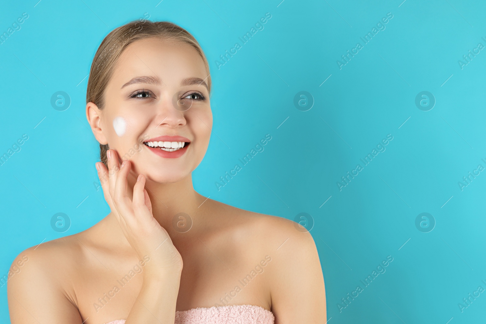 Photo of Young woman washing face with cleansing foam on light blue background, space for text. Cosmetic product