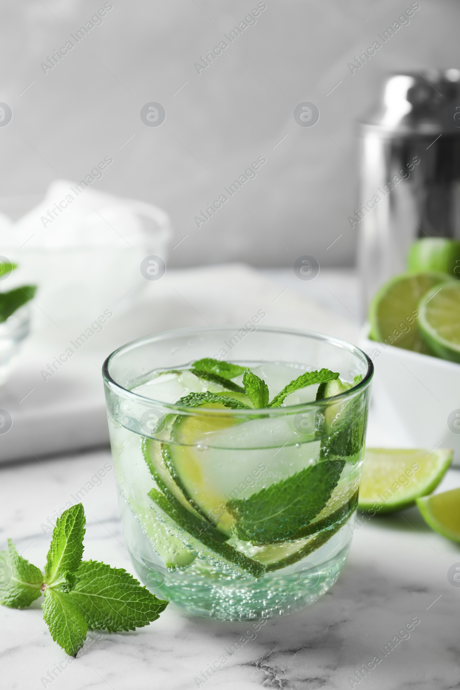 Photo of Refreshing beverage with mint and lime in glass on table