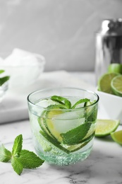 Photo of Refreshing beverage with mint and lime in glass on table