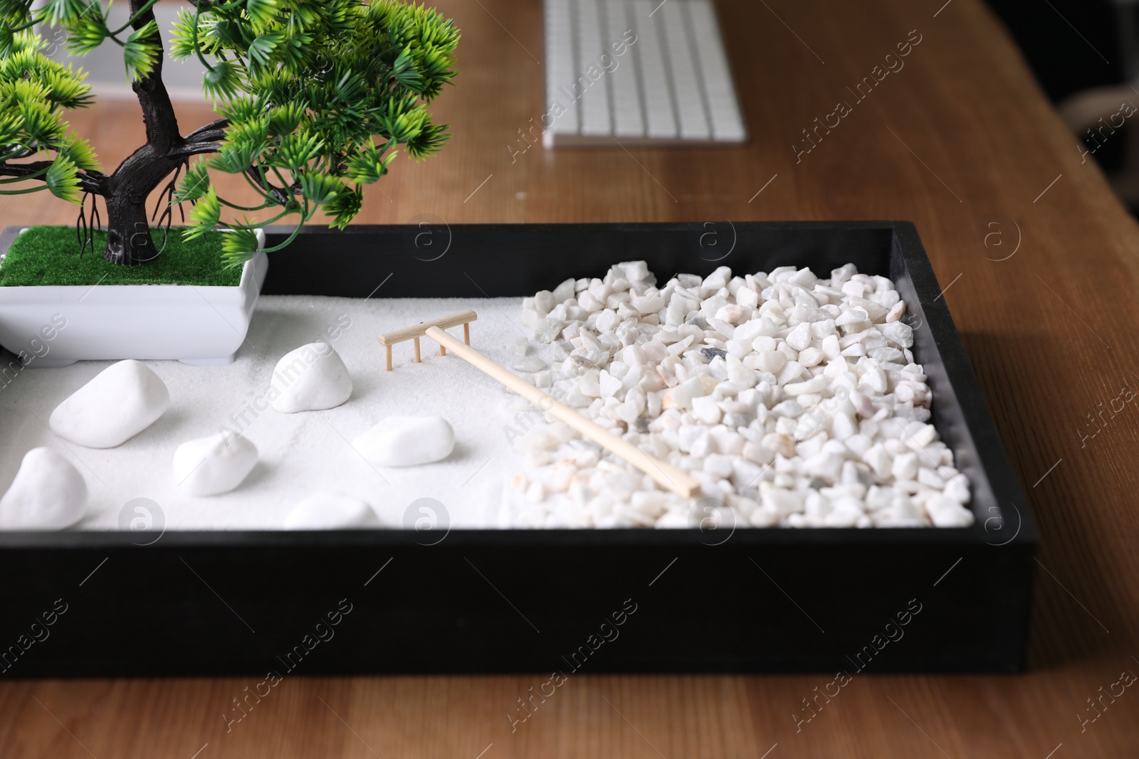 Photo of Beautiful miniature zen garden on wooden table, closeup