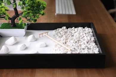 Photo of Beautiful miniature zen garden on wooden table, closeup