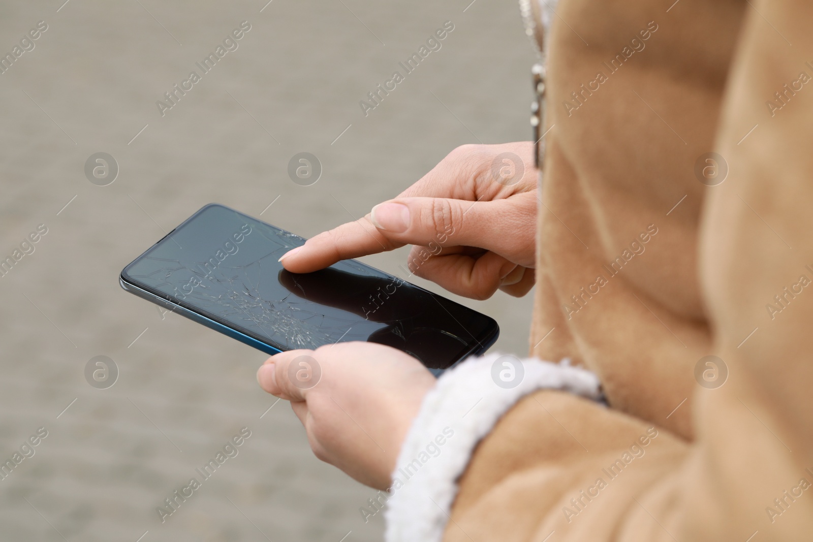 Photo of Woman holding damaged smartphone outdoors, closeup. Device repairing