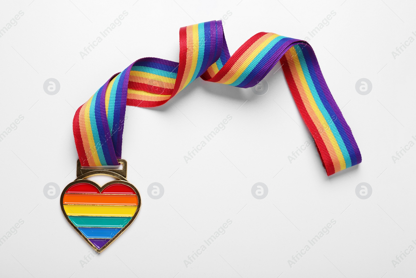 Photo of Rainbow ribbon with heart pendant on white background, top view. LGBT pride