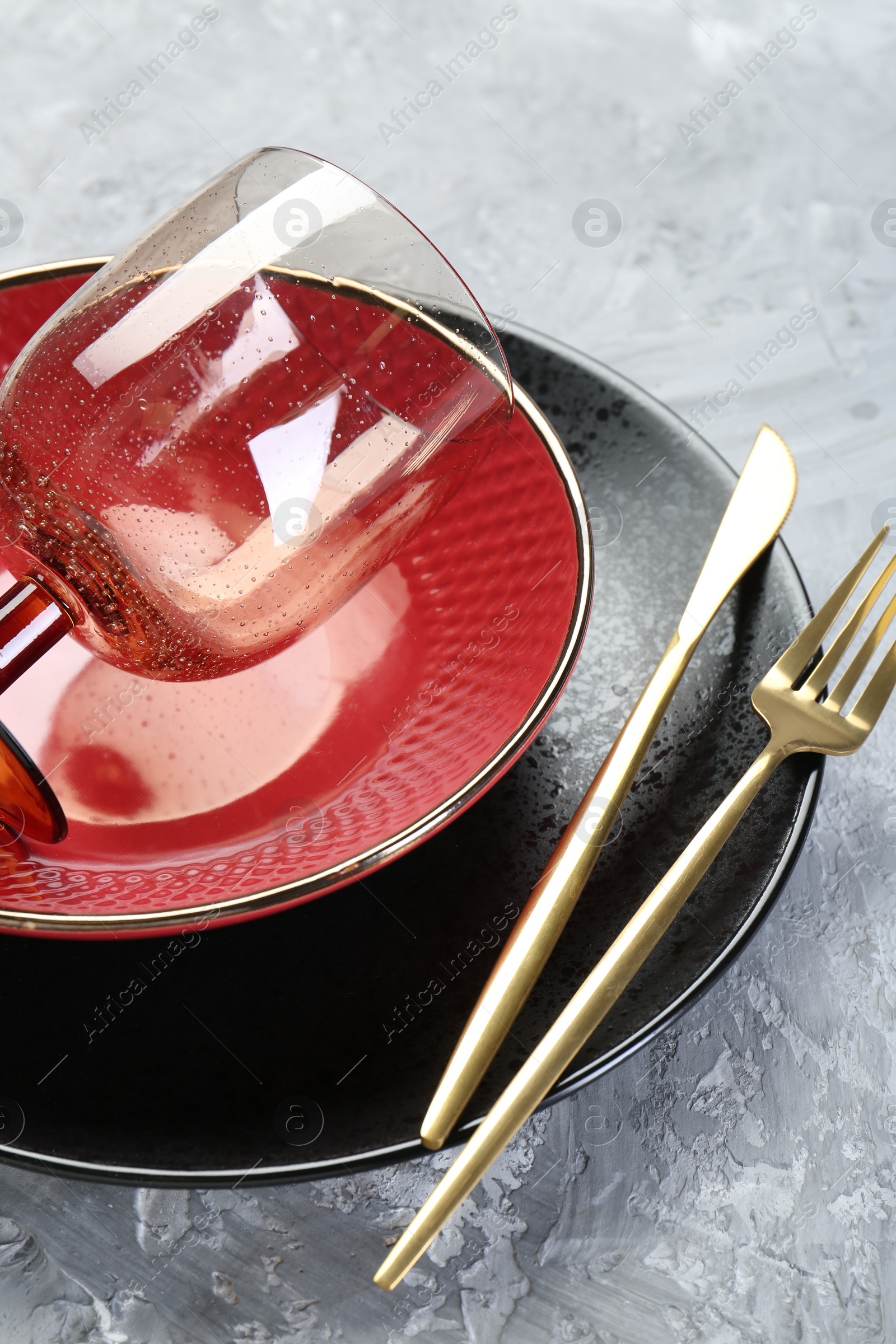Photo of Clean plates, bowl, glass and cutlery on gray textured table, closeup