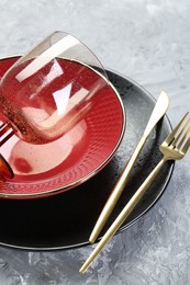 Clean plates, bowl, glass and cutlery on gray textured table, closeup