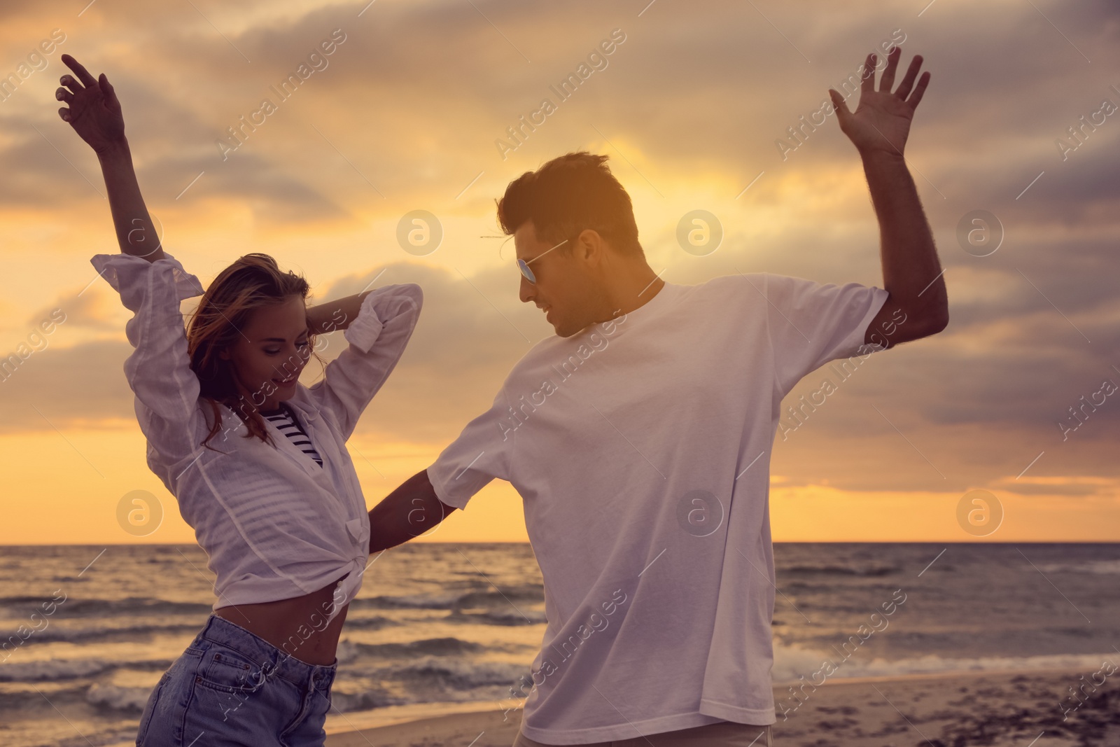 Photo of Happy couple dancing on beach at sunset