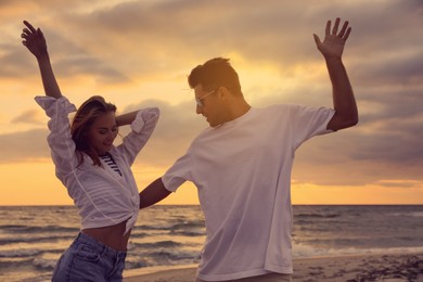 Photo of Happy couple dancing on beach at sunset