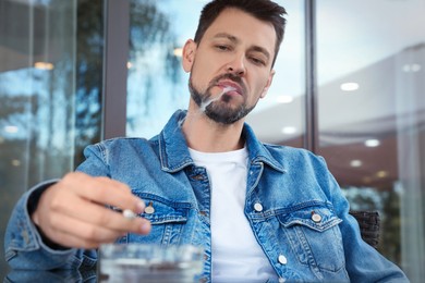 Photo of Handsome man smoking cigarette in outdoor cafe