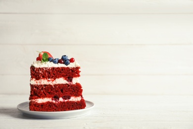 Plate with piece of delicious homemade red velvet cake and space for text on light background