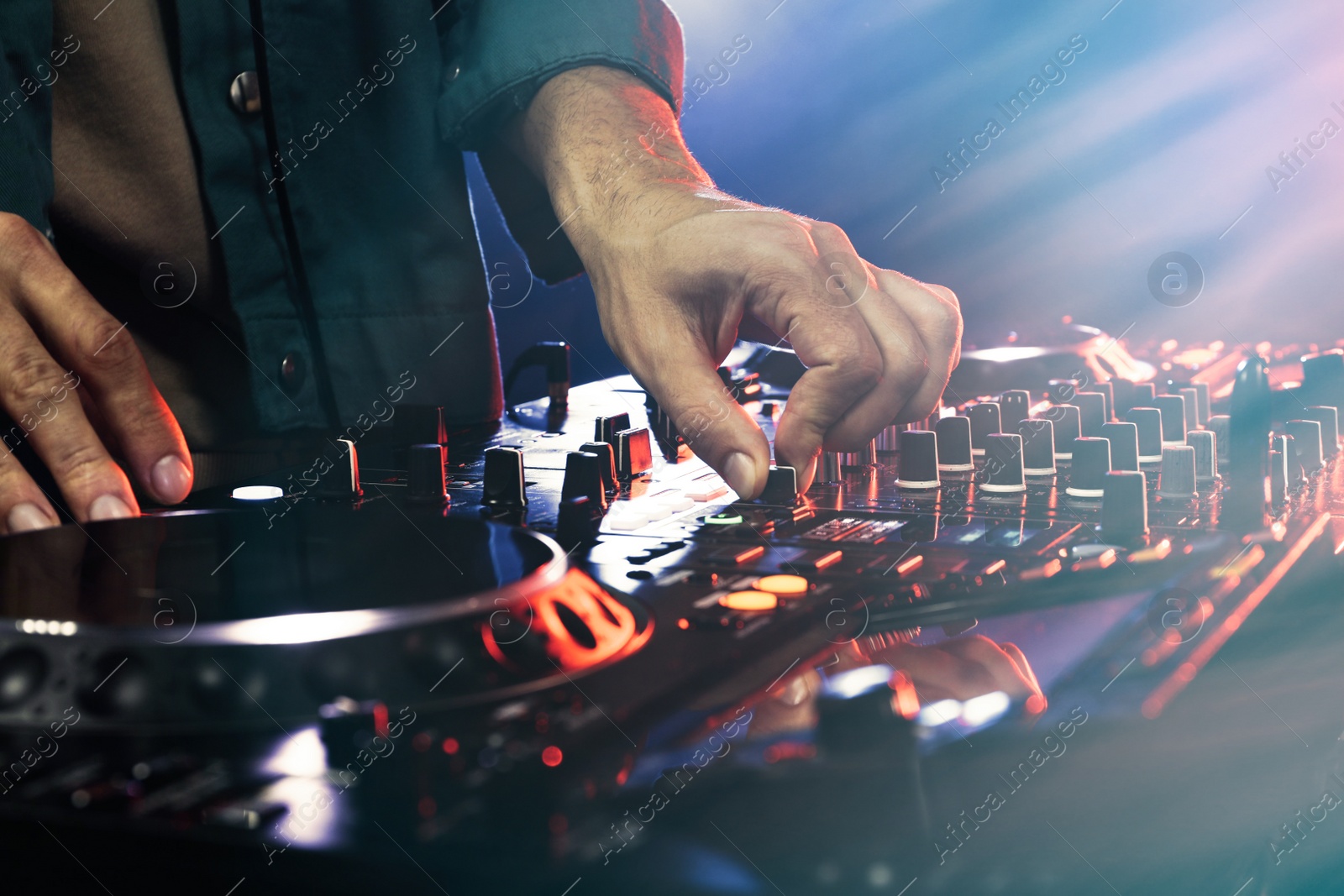 Photo of DJ creating music on modern console mixer in night club, closeup