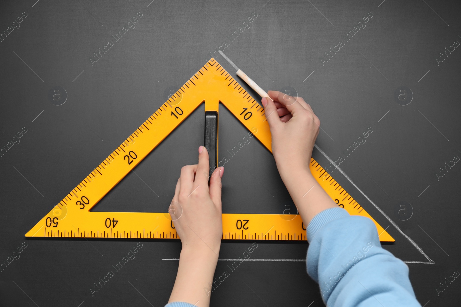 Photo of Woman drawing with chalk and triangle ruler on blackboard, closeup