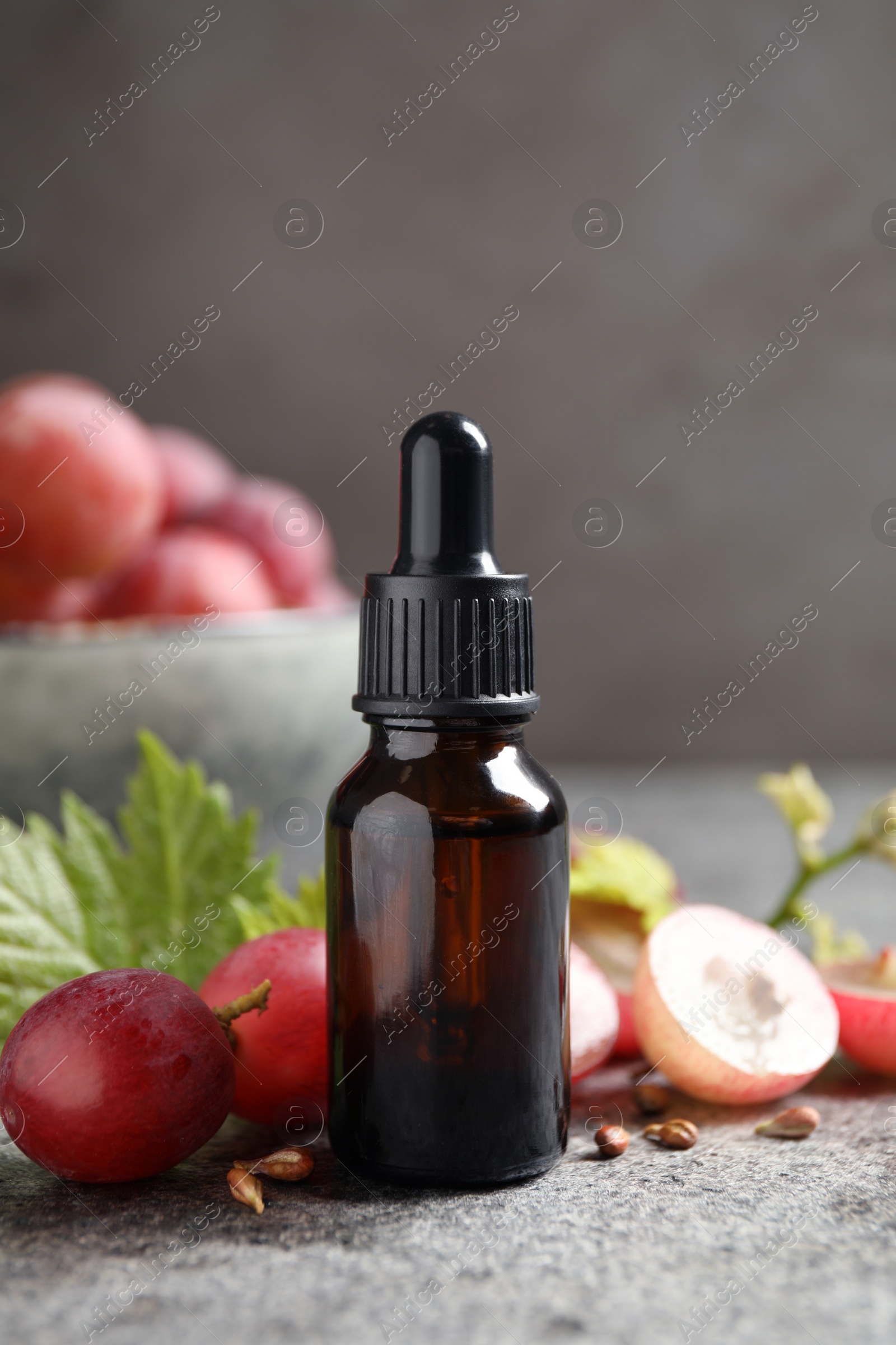 Photo of Bottle of natural grape seed oil on grey table. Organic cosmetic