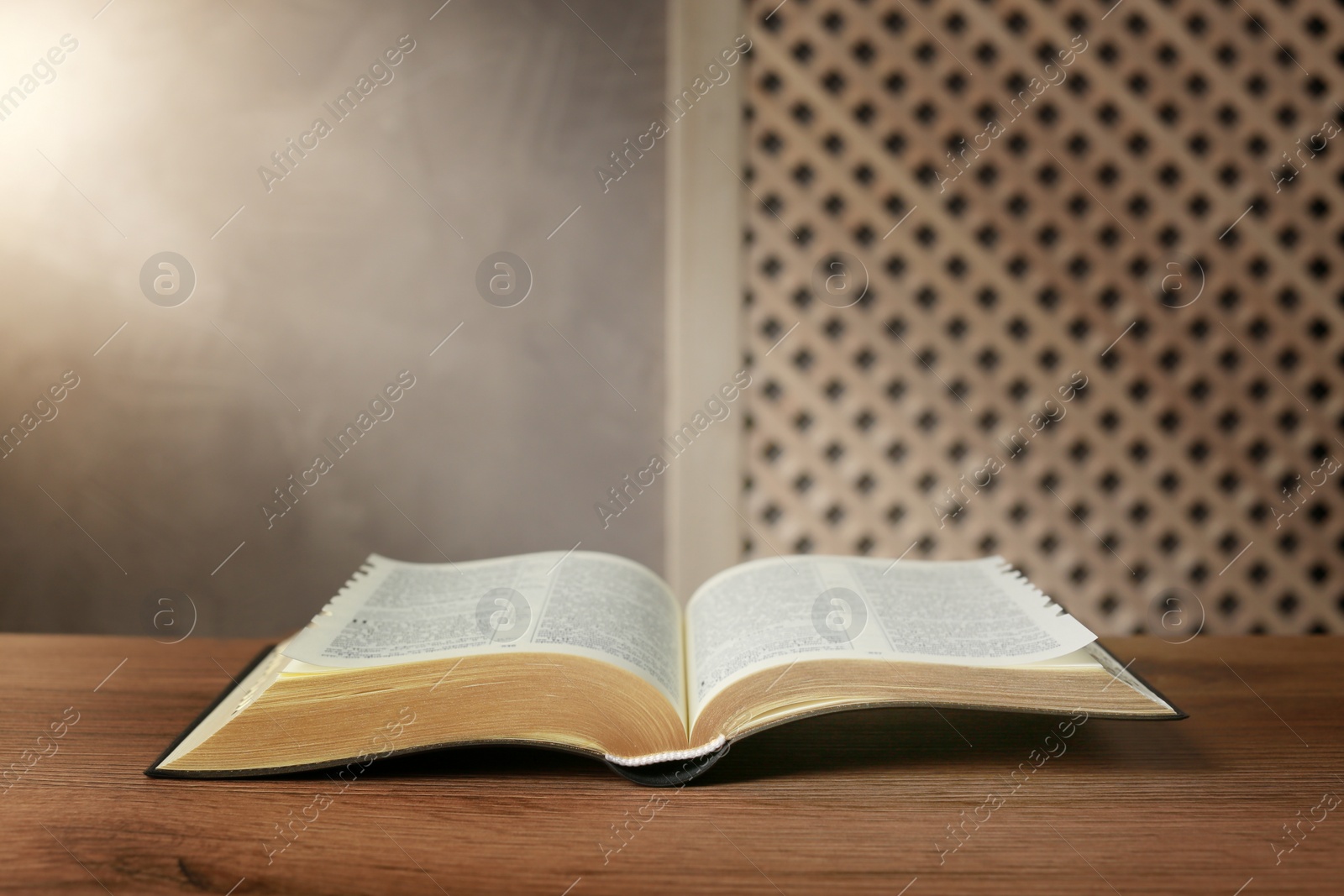 Photo of Beam of light over open Bible on wooden table