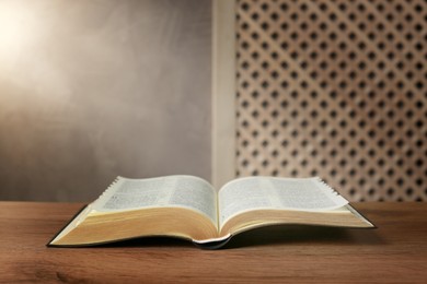 Photo of Beam of light over open Bible on wooden table