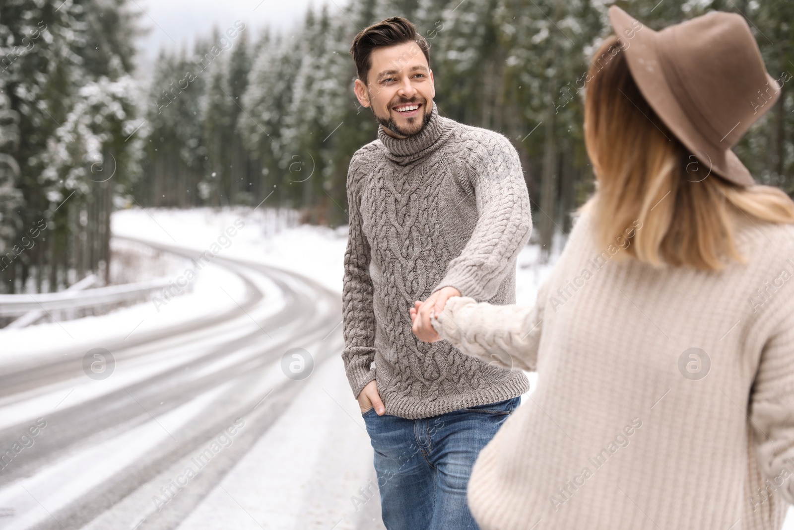 Photo of Couple walking near snowy forest, space for text. Winter vacation