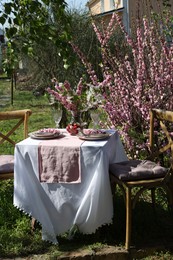 Stylish table setting with beautiful spring flowers in garden