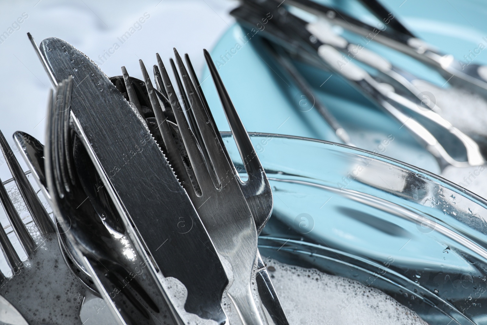 Photo of Glass bowl with silverware in foam, closeup