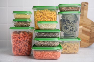 Photo of Plastic containers filled with food products on white table near tiled wall