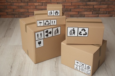 Photo of Cardboard boxes with different packaging symbols on floor. Parcel delivery