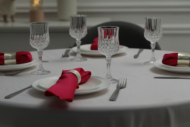 Photo of Color accent table setting. Glasses, plates, cutlery and pink napkins on table indoors