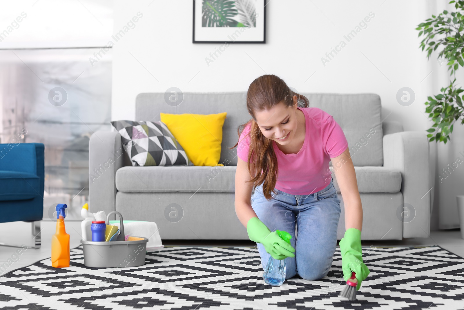 Photo of Woman cleaning carpet in living room