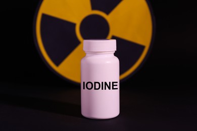 Photo of Plastic container of medical iodine and radiation sign on black background