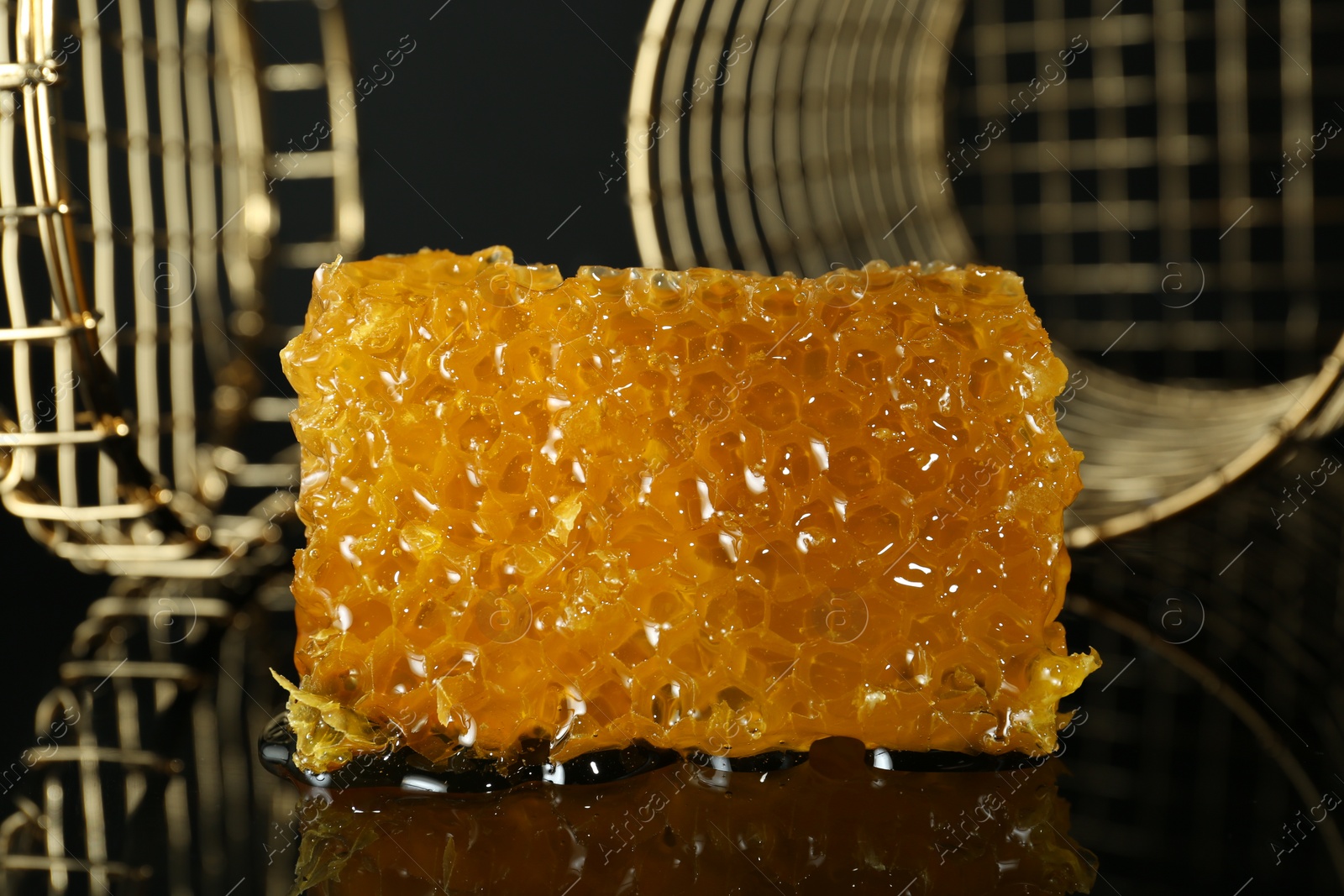 Photo of Piece of natural honeycomb with tasty honey on black background