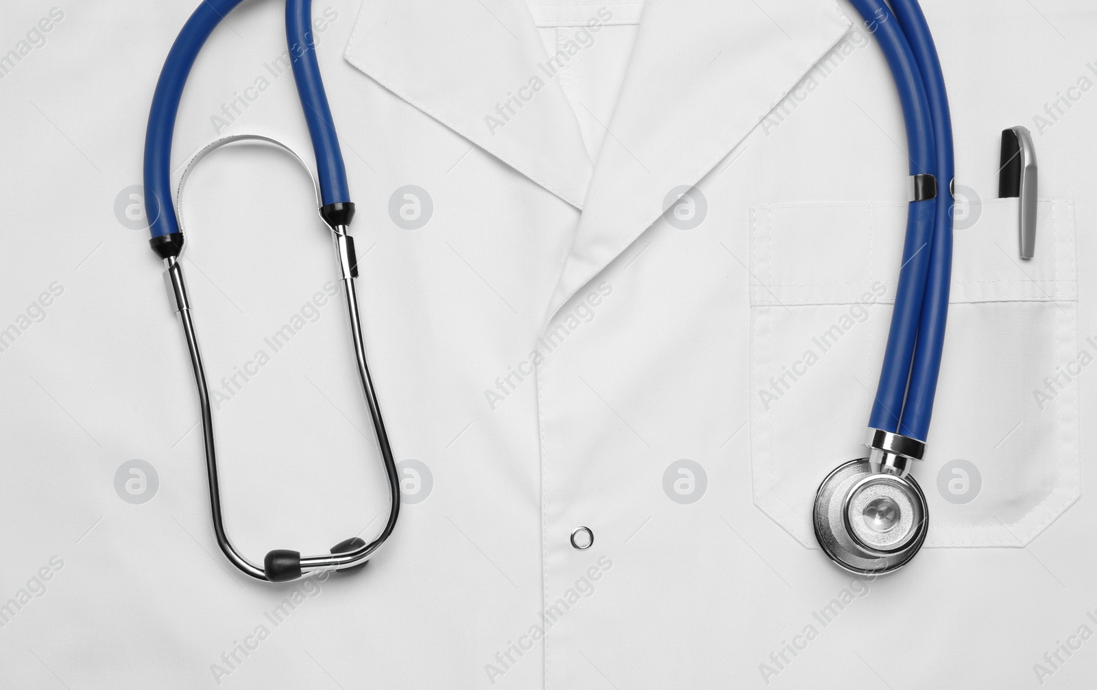 Photo of Stethoscope on white medical uniform, top view