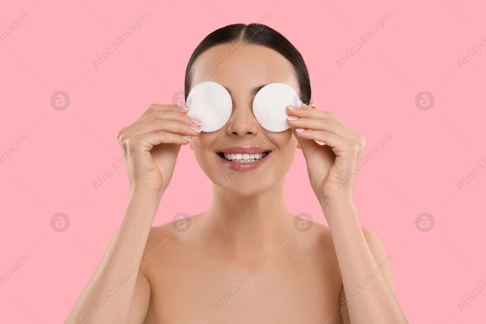 Photo of Beautiful woman removing makeup with cotton pads on pink background