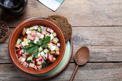 Photo of Delicious cold okroshka with kvass served on wooden table, flat lay and space for text. Traditional Russian summer soup