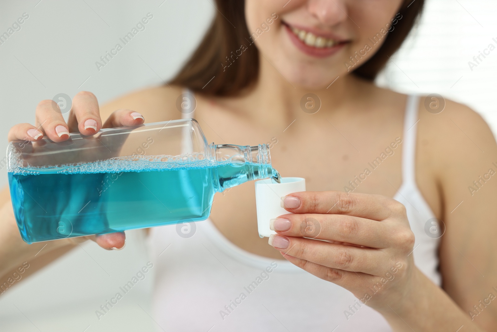 Photo of Young woman using mouthwash on blurred background, closeup