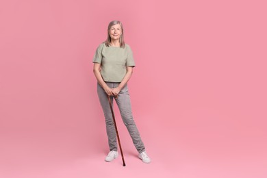 Photo of Senior woman with walking cane on pink background
