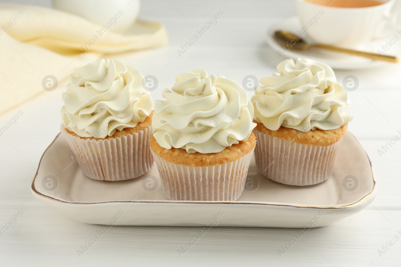 Photo of Tasty cupcakes with vanilla cream on white wooden table, closeup