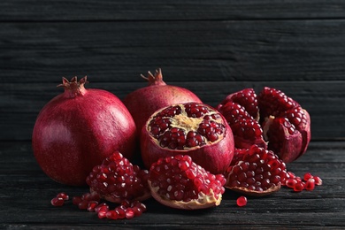 Photo of Ripe pomegranates and seeds on wooden table