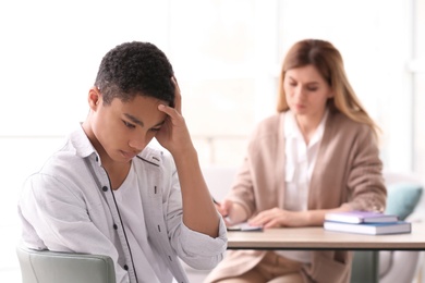 Photo of Young female psychologist working with teenage boy in office