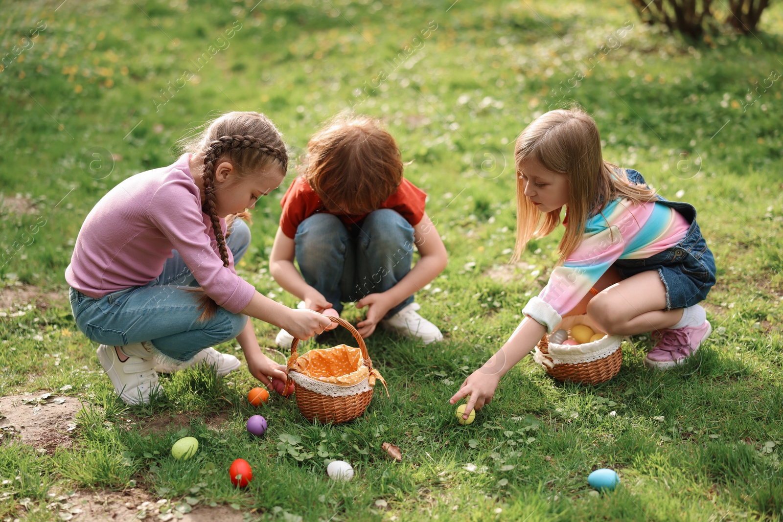 Photo of Easter celebration. Cute little children hunting eggs outdoors