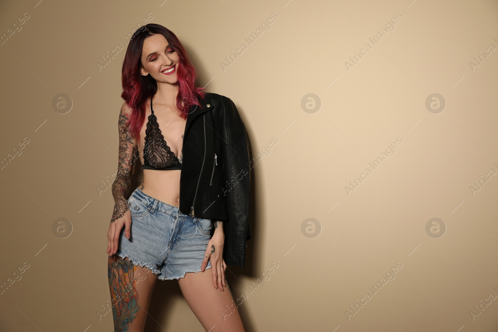 Photo of Beautiful woman with tattoos on body against beige background. Space for text