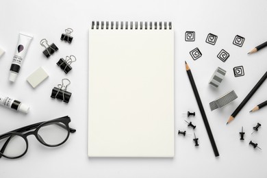 Photo of Composition with sketchbook, glasses and stationary on white background, top view