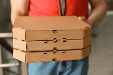 Photo of Man with pizza boxes indoors, closeup. Food delivery service