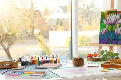 Photo of Artist's workplace with drawing, soft pastels and color pencils on table indoors