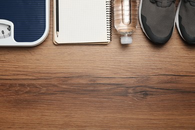 Photo of Weight loss concept. Flat lay composition with sneakers, scales and notebook on wooden table, space for text