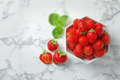 Photo of Bowl with ripe strawberries on marble background, top view