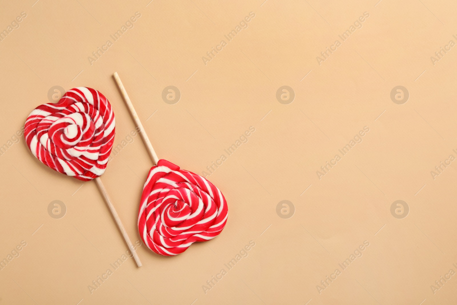 Photo of Sweet heart shaped lollipops on beige background, flat lay with space for text. Valentine's day celebration