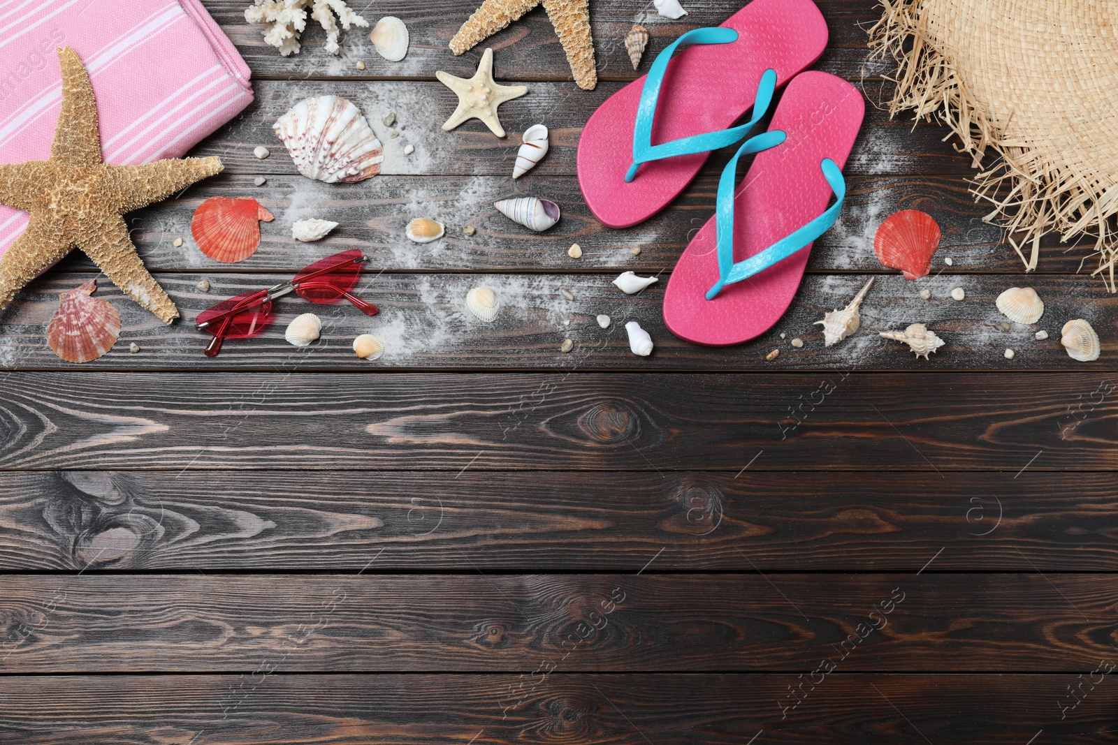 Photo of Stylish flip flops and beach objects on wooden background, flat lay. Space for text