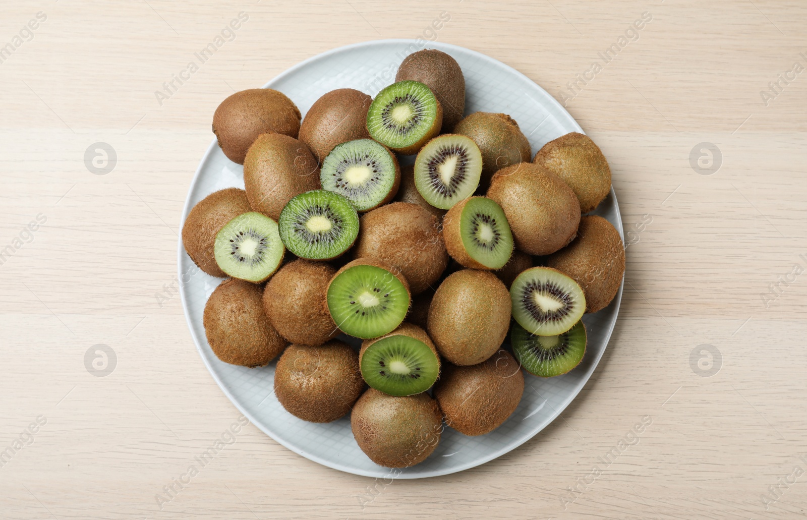 Photo of Fresh ripe kiwis on light wooden table, top view