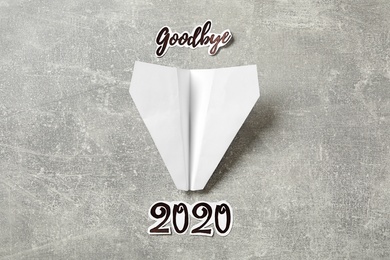 Photo of Text Goodbye 2020 and paper plane on grey background, flat lay